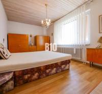 Rodinný dom s nádherným 8 árovým pozemkom na Kamennej ulici - Spálňa s podlahou s dreveným dekorom v rodinnom dome, s nábytkom a lustrami.