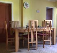 Dom s garážou na peknom rovinatom pozemku so šírkou 24m. - Jedáleň v rodinnom dome so stoličkami a stolom na podlahe s dreveným dekorom.