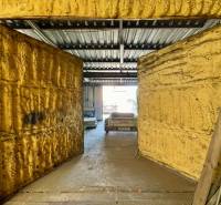 Na predaj objekt vhodný na podnikanie – Trenčín, Záblatie - Obchodné priestory s otvorenými dverami a kovovou strechou, v pozadí vidieť auto.