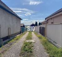 Stavebný pozemok so stavebným povolením - Janíkovce - 729 m2 - Úzka cesta medzi domami v lokalite Pozemky - bývanie, Nitra, vedúca k panoráme krajiny.