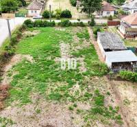 Stavebný pozemok 1365 m2 - Bardoňovo - Pozemky - bývanie v Bardoňove, ukazujú zalesnenú parcelu s vidieckymi domami na pozadí.