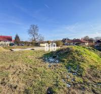 1786 m2 - základová doska - stavebné povolenie + projekt - Mojmírovce - Pozemok pripravený na stavbu bývania, zasnežená tráva, obklopený domami a strešnými krytinami.