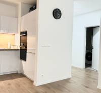 PRENÁJOM exkluzívny 2 izb byt POPRAD s loggiou 53,9 + 8,34 m2 - Kuchyňa v 2-izbovom byte s dreveným dekorom podlahy a bielym nábytkom.