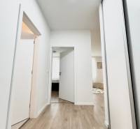 PRENÁJOM exkluzívny 2 izb byt POPRAD s loggiou 53,9 + 8,34 m2 - Chodba so svetlými stenami a podlahou s dreveným dekorom, vedúca do miestností 2-izbového bytu.