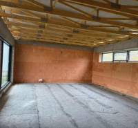 Rodinný dom - bungalov, Teplička nad Váhom - Interiér rodinného domu s veľkým oknom a stropnými trámami, prázdna miestnosť.