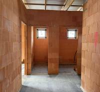 Rodinný dom - bungalov, Teplička nad Váhom - Interiér rodinného domu s priečkami z tehál, dve malé okná, betónová podlaha.