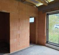 Rodinný dom - bungalov, Teplička nad Váhom - Nedokončený interiér v rodinnom dome s veľkým oknom a tehlovými stenami.