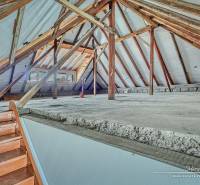 3-izbový moderne zrekonštruovaný rodinný dom v obci Jaslovské Bohunice - Povala v rodinnom dome s viditeľnými drevenými trámami a schodiskom.