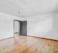 3-izbový moderne zrekonštruovaný rodinný dom v obci Jaslovské Bohunice - Izba v rodinnom dome s bielymi stenami a podlahou s dreveným dekorom.