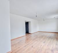 3-izbový moderne zrekonštruovaný rodinný dom v obci Jaslovské Bohunice - Priestranná izba v rodinnom dome s podlahou s dreveným dekorom a bielymi stenami.