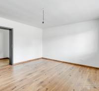 3-izbový moderne zrekonštruovaný rodinný dom v obci Jaslovské Bohunice - Izba s bielymi stenami a podlahou s dreveným dekorom v rodinnom dome.