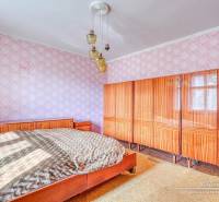 REZERVOVANÉ Starší 2-izbový rodinný dom v obci Dobrá Voda - Spálňa v rodinnom dome s veľkou posteľou, skrinkou a lustrom na strope.