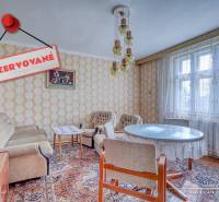 REZERVOVANÉ Starší 2-izbový rodinný dom v obci Dobrá Voda - Interiér rodinného domu s vintage nábytkom, tapetami a veľkým oknom s čipkovanou záclonou.