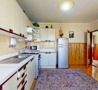 Rodinný dom, Kamienka, okr. Stará Ľubovňa - Kuchyňa rodinného domu s retro chladničkou, mikrovlnkou a podlahou s dreveným dekorom.