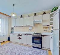 Rodinný dom, Kamienka, okr. Stará Ľubovňa - Kuchyňa s bielou linkou, jedálenským stolom a podlahou s dreveným dekorom v rodinnom dome.