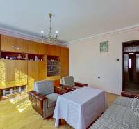 Rodinný dom, Kamienka, okr. Stará Ľubovňa - Obývačka v rodinnom dome s knihovníčkou, kreslami a podlahou s dreveným dekorom.