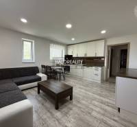 REZERVOVANÉ - Predaj, trojizbový byt Bošany - EXKLUZ... - Obývačka s kuchynskou linkou, sivou pohovkou a jedálenským stolom v 3-izbovom byte.