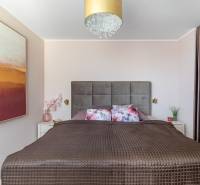 Moderný rodinný dom s bazénom v Trnave!!! - Spálňa so širokou posteľou, dekoratívnymi vankúšmi, obrazom a skrytým úložným priestorom v 4-izbovom byte.