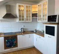 Bývanie  v Starom meste ? Jedinečná príležitosť skvelého bytu - Kuchyňa v 3-izbovom byte s drevenou podlahou, bielymi skrinkami a úložným priestorom.