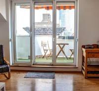 Bývanie  v Starom meste ? Jedinečná príležitosť skvelého bytu - Obývacia izba s balkónom, drevená podlaha, stolička a stolík v 3-izbovom byte.