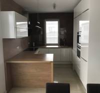 3 izbový byt, 50 m2 terasa, 2PS, Gajarská ulica, Záhorská Bystrica - Kuchyňa v 3-izbovom byte s bielymi skriňami a podlahou s dreveným dekorom.