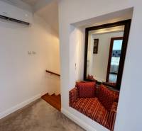 PREDAJ : ŠTÝLOVÝ RODINNÝ DOM S BAZÉNOM, KOMÁRNO - Rodinný dom zobrazuje schody s dreveným dekorom, zrkadlo a sedací kútik s vankúšmi.