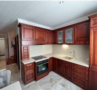 PREDAJ : ŠTÝLOVÝ RODINNÝ DOM S BAZÉNOM, KOMÁRNO - Kuchyňa s tmavými drevenými skrinkami a podlahou s dreveným dekorom v rodinnom dome.