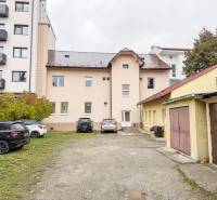 Na predaj ambulancia 101m2, Bratislavská ul. - Žilina - Budova na Bratislavskej ulici v Žiline, obklopená autami a garážami, vhodná pre kancelárie.