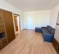 NA PREDAJ 1-IZBOVÝ BYT (37m2), SENICA, HVIEZDOSLAVOVA UL. - Obývacia izba v 1-izbovom byte s podlahou s dreveným dekorom, sedačkou a skriňami.