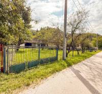 5i RD s garážou, Čierna Lehota, okr. Bánovce n./B. - Rodinný dom v Čiernej Lehote s veľkou záhradou a kovovým plotom pri ceste.