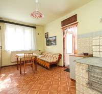 5i RD s garážou, Čierna Lehota, okr. Bánovce n./B. - Kuchyňa v rodinnom dome s kachľovým sporákom a podlahou s dreveným dekorom.