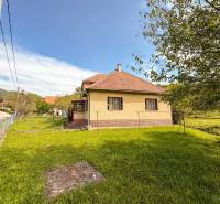 5i RD s garážou, Čierna Lehota, okr. Bánovce n./B. - Rodinný dom v Čiernej Lehote so záhradou, trávnikom a cestou v pozadí.