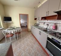 3 izbový byt  balkónom Topoľčany Juh - Kuchyňa v 3-izbovom byte s rohovou linkou, stolom a televízorom na stene.