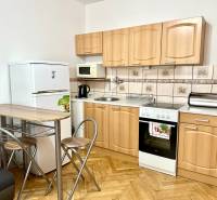 GARSONKA NA PRENÁJOM – VOĽNÁ IHNEĎ (sídlisko Východ) - Kuchyňa v garsónke s podlahou s dreveným dekorom, so spotrebičmi a sedením.