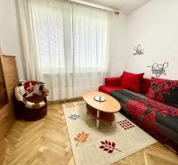 GARSONKA NA PRENÁJOM – VOĽNÁ IHNEĎ (sídlisko Východ) - Garsónka s podlahou s dreveným dekorom, červenou sedačkou a kreslom.