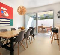 NA PREDAJ moderná vila /251 m²/ v atraktívnej lokalite, ostrov Krk - Svetlá jedáleň vo Vile s dreveným stolom, farebným obrazom a terasou.