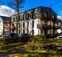 Na predaj krásny apartmám v Štrbe - Exteriér bytového domu na Lúčnej ulici v Štrbe so zaparkovanými vozidlami a upraveným okolím.