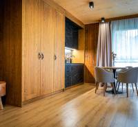 Na predaj krásny apartmám v Štrbe - Izba v 2-izbovom byte s kuchynským kútom, drevenými stenami a podlahou s dreveným dekorom.