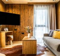 Na predaj krásny apartmám v Štrbe - Obývacia izba v 2-izbovom byte s pohovkou, podlahou s dreveným dekorom a konferenčným stolíkom.