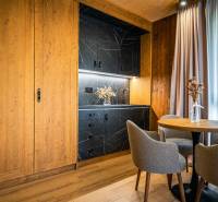 Na predaj krásny apartmám v Štrbe - Kuchynský kút s čiernym mramorovým dekorom a podlaha s dreveným dekorom v 2-izbovom byte.