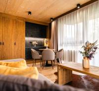 Na predaj krásny apartmám v Štrbe - Interiér 2-izbového bytu s podlahou s dreveným dekorom, štýlovým nábytkom a závesmi.