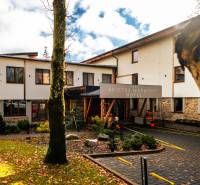 Na predaj krásny apartmám v Štrbe - Budova hotela so stromami a padajúcim lístím v Štrbe na ulici Lúčna.