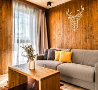 Na predaj krásny apartmám v Štrbe - Obývacia izba v 2-izbovom byte s podlahou s dreveným dekorom a dekoráciou na stene.