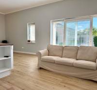 REZERVOVANÉ Na prenájom 4 izbový rodinný dom, Pata, ul. Pod Vinohradmi - Svetlá obývacia izba s podlahou s dreveným dekorom, pohovkou a výhľadom do záhrady.