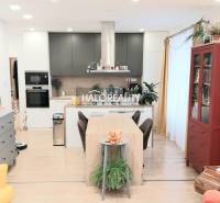 Predaj, trojizbový byt Komárno - Kuchyňa v 3-izbovom byte s podlahou s dreveným dekorom, jedálenský stôl a knižnica.