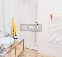 Predaj, trojizbový byt Komárno - Kúpeľňa s podlahou s dreveným dekorom, umývadlom na doske a bielymi stenami v 3-izbovom byte.