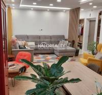 Predaj, trojizbový byt Komárno - Obývacia izba v 3-izbovom byte s posedením, kvetmi a podlahou s dreveným dekorom.