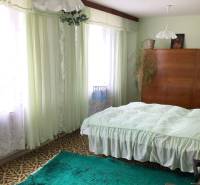 Na predaj rod. dom v obci Radošovce - Vieska, okr. Skalica. - Spálňa v rodinnom dome s kobercami, záclonami a drevenou skriňou.