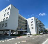 Nájom garsónka, 34 m2 | kryté parkovanie | Odevná, Trenčín - Budova na Odevnej ulici v Trenčíne, Garsónka, biela fasáda, parkovanie a cesta.