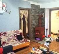 HD reality, Predaj 2-izbového bytu, Veľký Krtíš - Obývacia izba v 2-izbovom byte s kachľovou pecou a podlahou s dreveným dekorom.